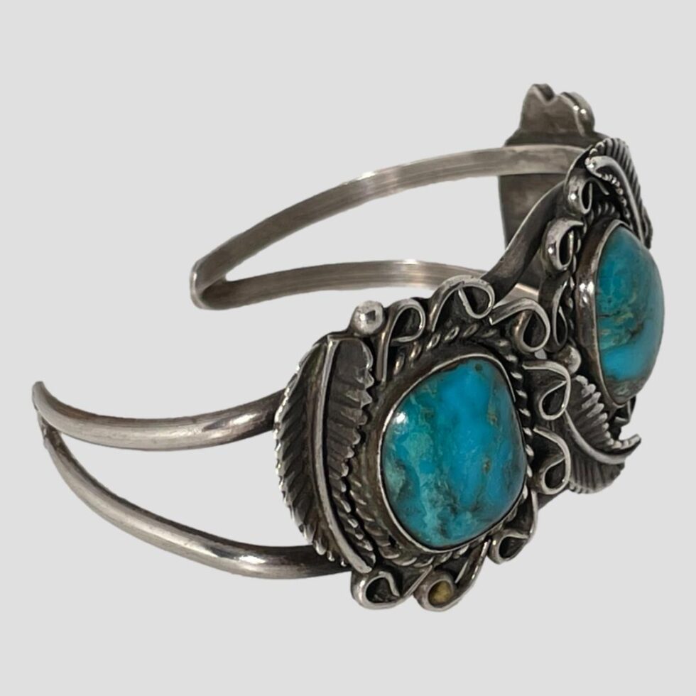 Photo of antique Navajo turquoise cuff bracelet displayed on a flat surface and shown in close up with bracelet front facing right.