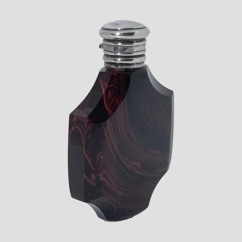 Photo of French scent bottle this time turned slightly so the opening side from the main photo is now pointing towards the bottom right corner. The slimmer width of the bottle can be seen.