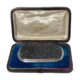 Main photo of antique tourmaline specimen brooch displayed inside its fitted case. The brooch is a wide oblong shape bordering on rectangular. The tourmaline is a grey/black colour and in a natural crystalline form and not polished smooth. The silver frame around the tourmaline is relatively thin in comparison but nicely executed with a plain flat silver frame around the edge of the tourmaline followed by a twisted silver band and finally set on a smooth round edged silver main frame. This brooch is all about the tourmaline! Black tourmaline is renowned for grounding the mind, relieving stress and shielding from negativity. Owing to its size and weight, this brooch would ideally suit a heavy overcoat or jacket.