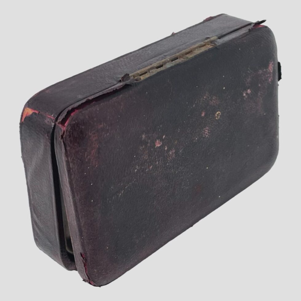 Photo of the case shown upright on its front showing the base. There is quite some wear here with peeling of the leather (also visible peeling on the corner of the top of case)
