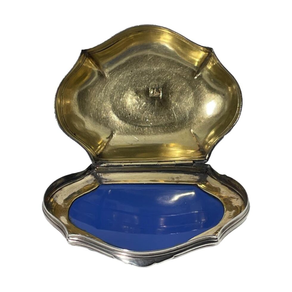 Photo looking into the box which has a gilt interior. The lid is in the foreground and the bottom of the box is back. The box is top heavy so will tip over when open. The hallmark for William Lestourgeon (WL with a fish above) can be seen inside.