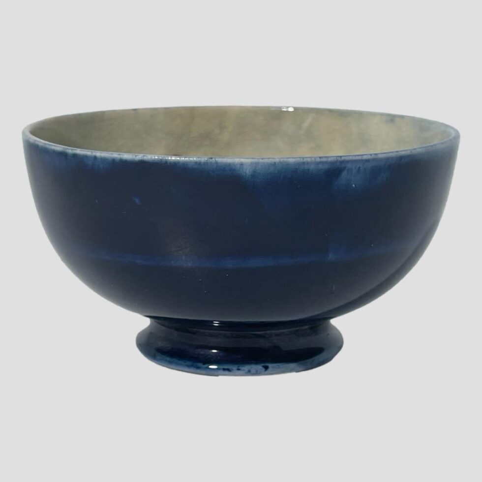Photo of small Moorcroft bowl seen from an eye level. Pretty plain with dark blue exterior and just visible faun grey interior.