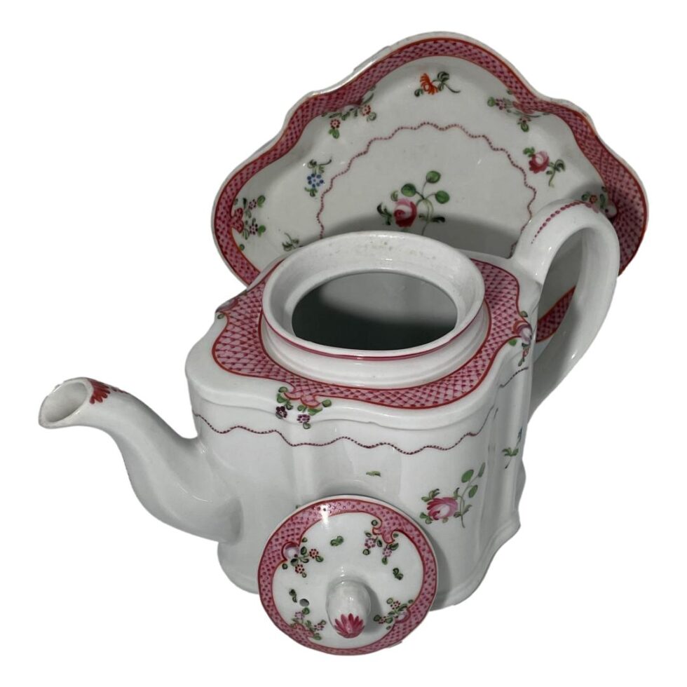 Photo of New Hall teapot displayed in the same fashion as the main photo but this time from a slightly higher angle looking diagonally down and with the lid removed and placed leaning against and in front of the teapot showing the pink netting design clearly to all 3 pieces.