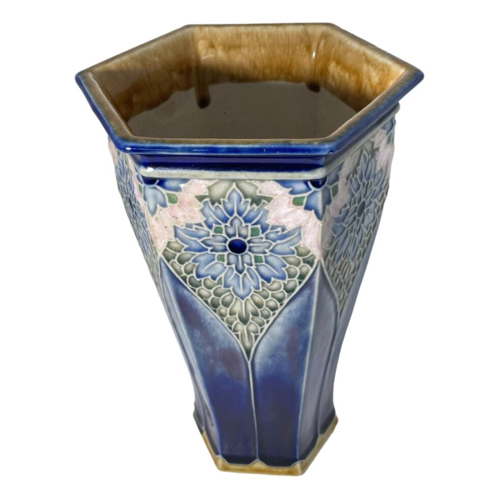 Photo of the hexagonal Doulton vase this time seen from a slightly raised angle peeking into the mouth. The mustard yellow glaze on inside of rim is visible with the running of the glaze.