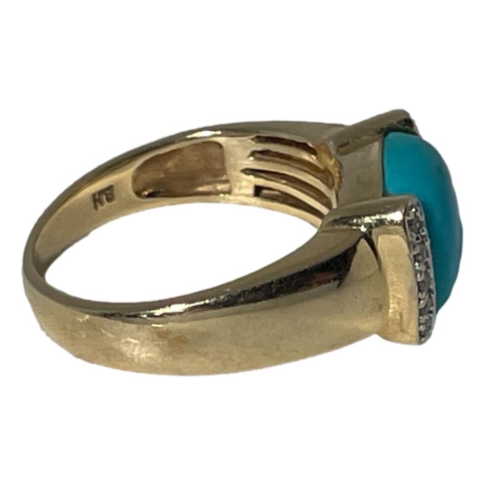 Photo of turquoise ring this time on a flat surface with the ring front facing right. The makers initials are visible to the inside band (B.H)