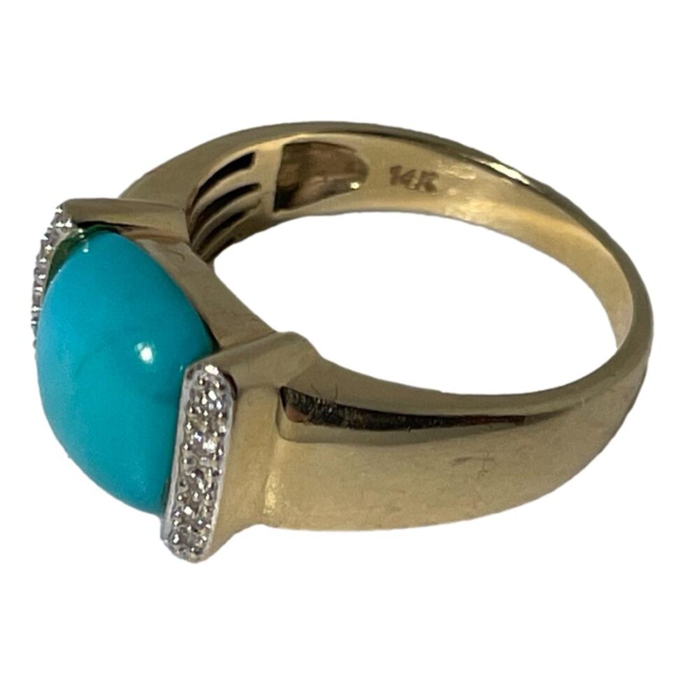 Photo of ring still on a flat surface with the ring front facing to the bottom left corner. The 14k hallmark is visible to the inside band.