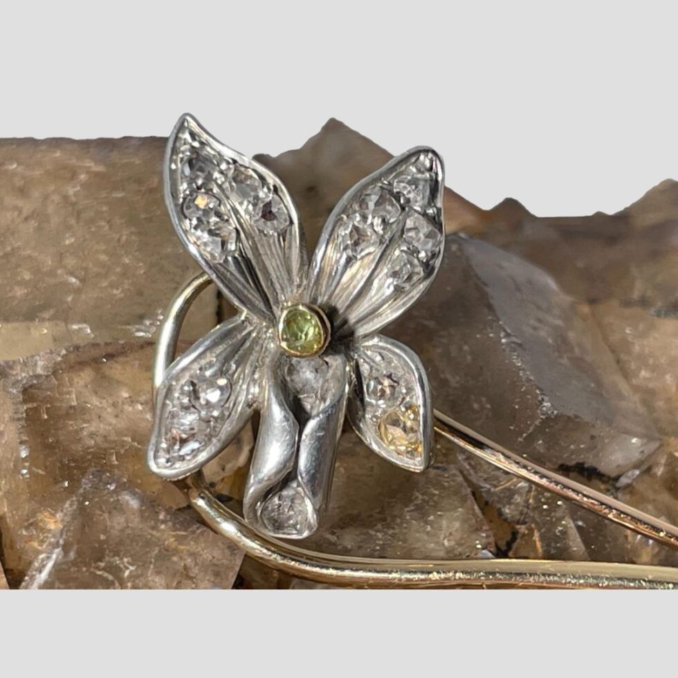 Close up photo of the orchid flower head seen from the front. The brooch is still displayed on the rock of natural river quartz which has a pink sandy colour.