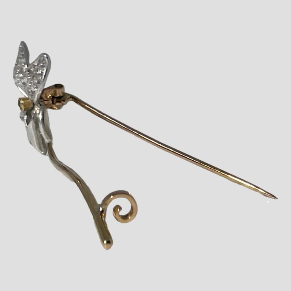 Photo of the brooch still displayed being propped up by its pin this time shown from a side angle with the flower head facing left and in the background. The pin clasp is visibe and also all the gold points of this brooch are clearly shown here.