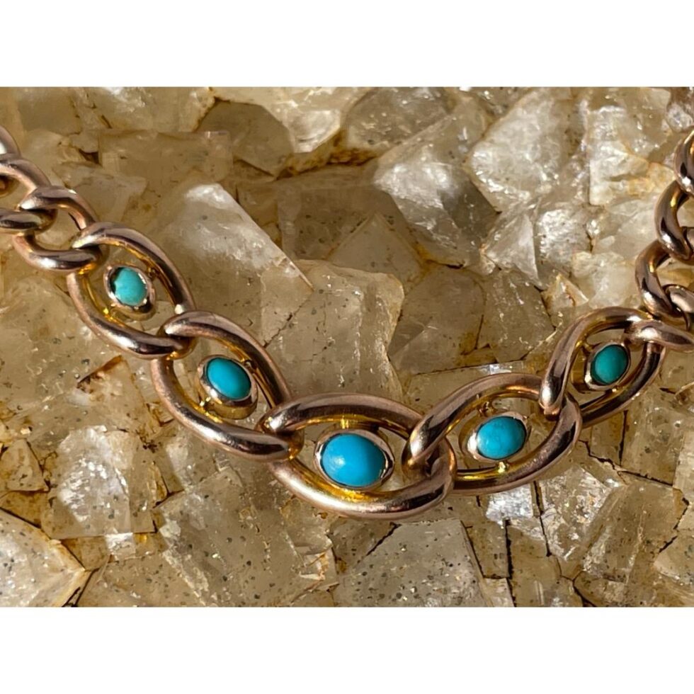 A close up photo of the 5 turquoise stones still displayed on top of a rock of natural river quartz.