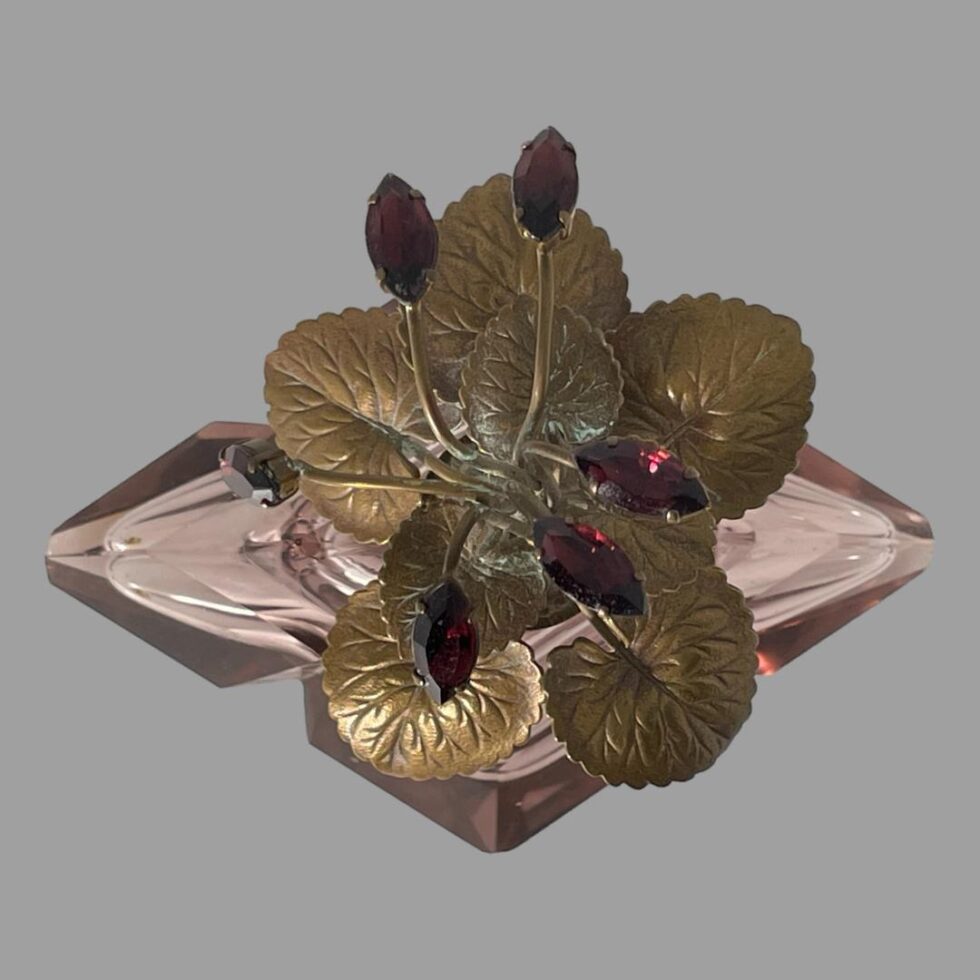 Photo looking straight down at the top of the Irice scent bottle looking at the purple rhinestone 'flowers' and the gilt metal leaves.