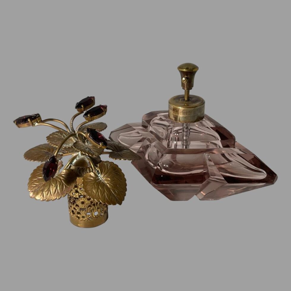 Photo of Irice scent bottle with lid removed and placed in the lower left side. Seen from a near eye level angle, The tip of the pump spray nozzle is visible.
