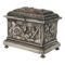 Main photo of French repousse jewellery casket displayed from a near eye level with the front opening side facing towards the bottom left and one side visible facing the bottom right corner. The casket sits on 4 feet which appear quite dainty for the solid and heavily embossed (repousse) casket. The base and top of lid jut out a little over the main body of the casket. The scenes on the sides show a lone bird, possible a peacock upright and looking towards the other side which shows a cockerel with 2 hens in a yard with a prowling fox on the very left. Some of the silver plate has worn off and the copper hue is coming through on the hens breasts and a small patch on the head of the cockerel and fox. This wear and copper exposure adds extra depth & charm to the casket.