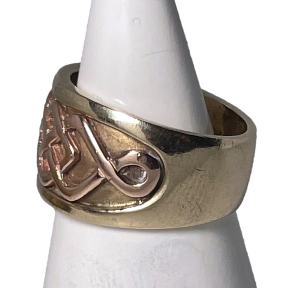 Photo of Clogau ring still displayed on a white cone shaped display stand with the ring front facing left and one shoulder visible.