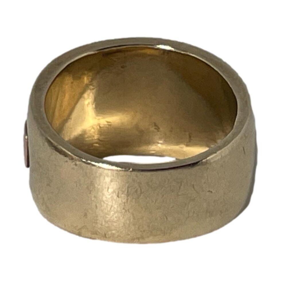 Photo of ring displayed on a flat surface displayed with ring front facing away from camera and the back band in the foreground.