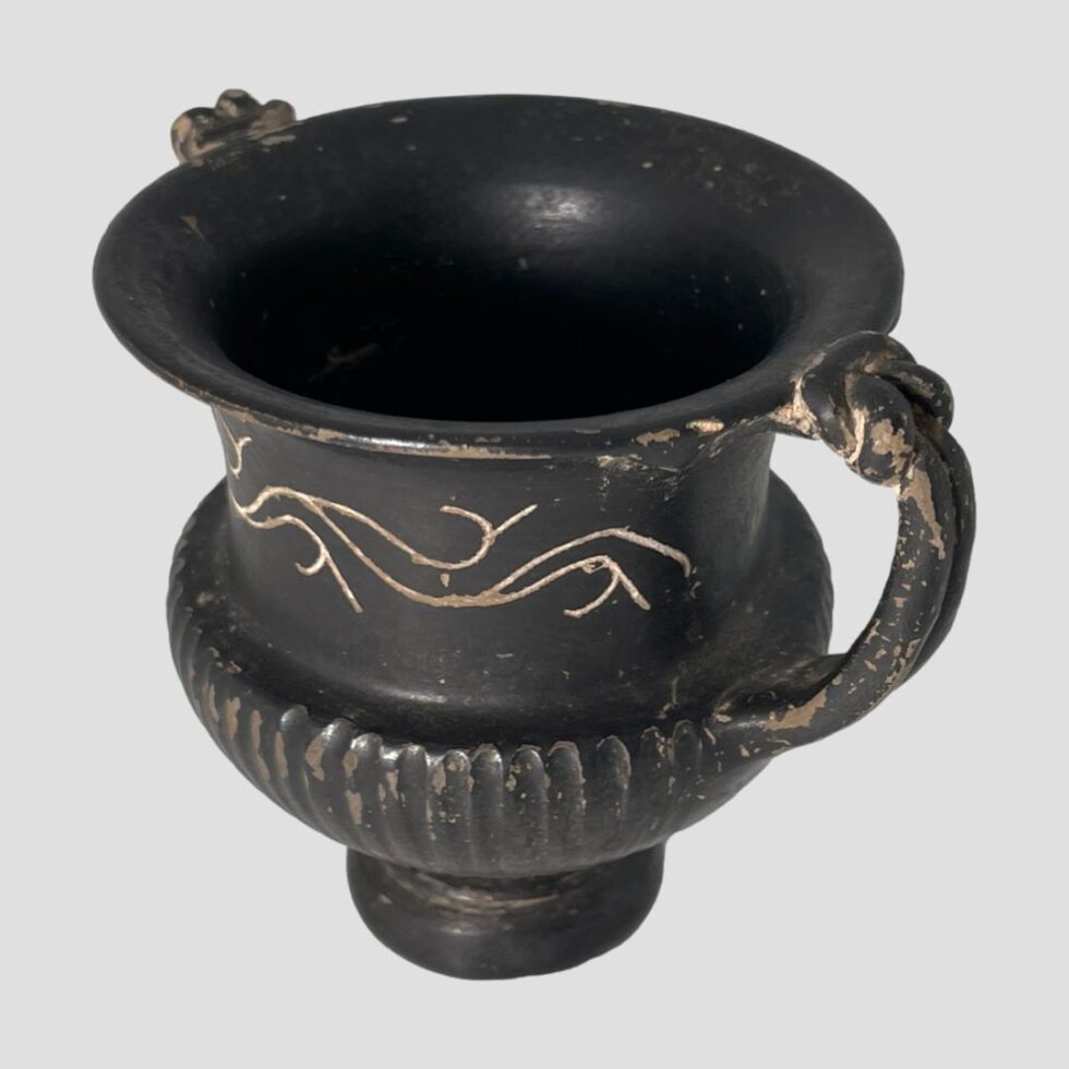 Photo of small Romano-Greek urn seen this time turned slightly so the handles are now at top left and bottom right corner. The angle is slightly raised so we are just peering into the mouth.
