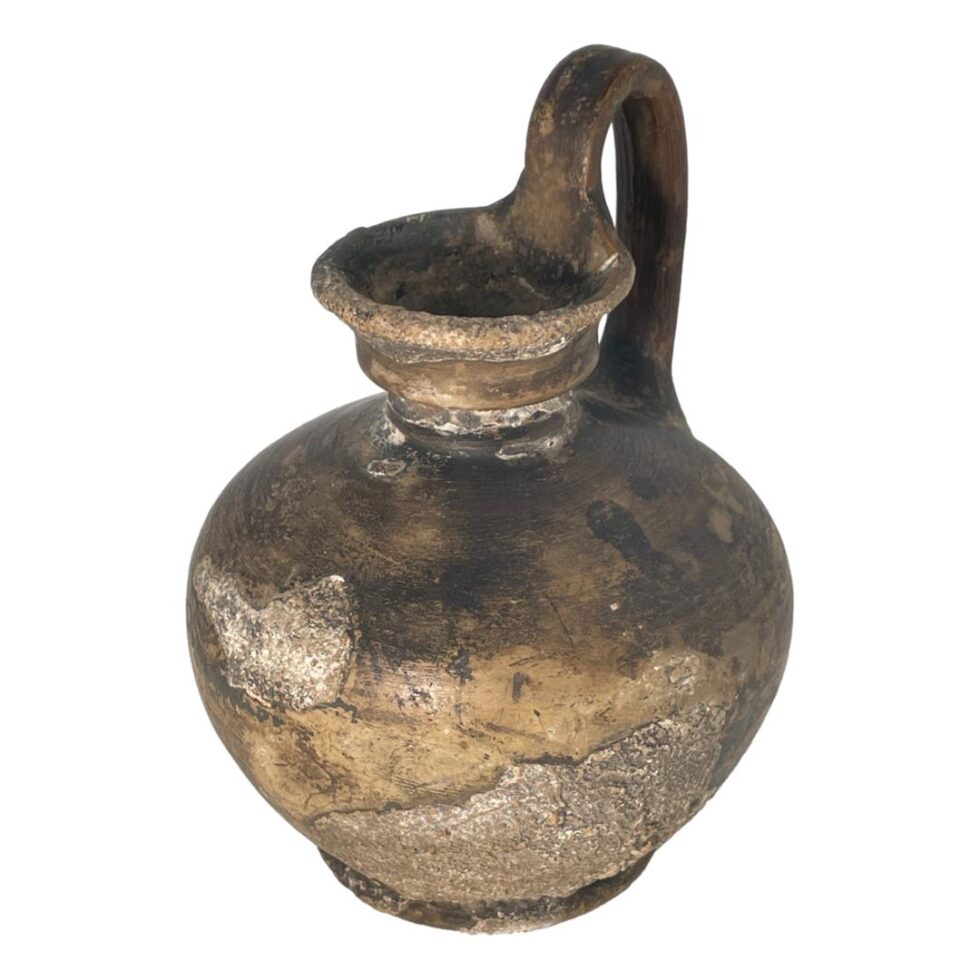 Photo of Roman wine jug this time slightly turned with the handle now in the top right corner. The fossilisation extends around the front of the jug.