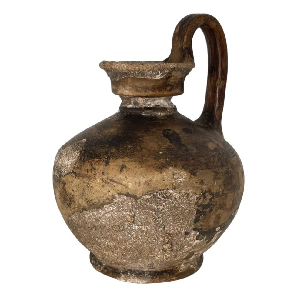 Photo of Roman shipwreck wine jug seen from an eye level with focus on the fossilisation area. The handle is slightly turned towards the back right corner.