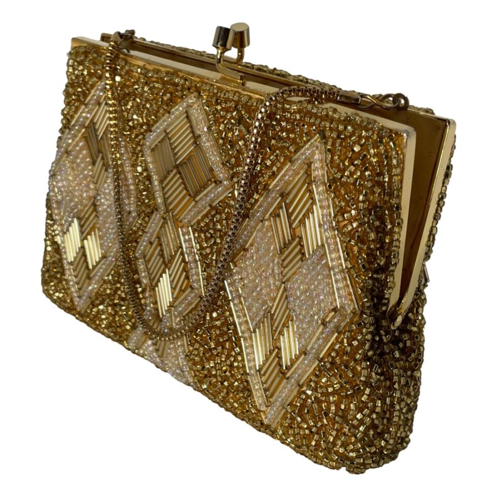 Main photo of vintage gold beaded bag seen from an eye level displayed diagonally with the sides in the top left and bottom right corners. One flat side of the bag is facing to the bottom left. This heavily beaded bag has a base of small gold beads and a design on both sides of diamond shaped panels at either end and joined double diamond at the centre. These panels have gold tubes and shimmering small white beads. The gilt metal chain is a round box chain and good thickness. Finished with a gilt metal frame and clasp. The bag is shown ajar.