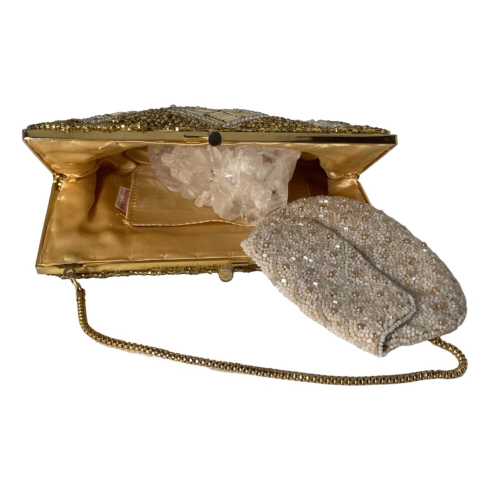 Photo of gold beaded bag laid flat and shown open with the small purse just out to the right. The bad is being held open by a rock of quartz crystal.