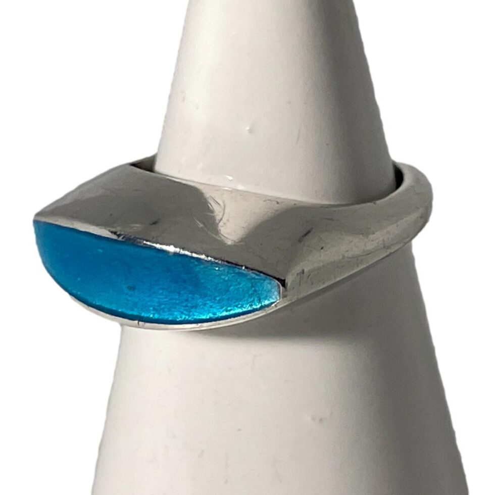 Photo of Just Andersen ring still displayed on the cone shaped stand this time with the ring front facing towards the bottom left corner. At this angle, it is possible to see how much the ring front sticks out from the band. Unlike other rings that sit high on the finger, this one is smooth on all sides so will not catch which is great bonus.