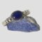 Main photo of Artie Yellowhorse cuff bracelet displayed on top of a small rock of lapis lazuli with the bracelet front forward facing. The bracelet is slightly angled down to the left so laid diagonally across the rock. It has a generous sized but not huge oval lapis cabochon with a double rope twist frame which is then stuck onto the cuff band, To either side of the lapis on the flat cuff band are 3 graduating silver balls starting with largest closest to the lapis. A very handsome chunky piece of quality Navajo jewellery.