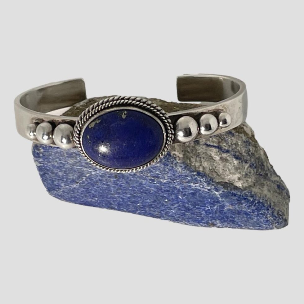 Photo of lapis cuff bracelet still on top of the small rock of lapis this time with the bracelet straight and we are looking a little downward from above. The lapis of the cuff and the lapis rock are 2 very different shades, the lapis on bracelet being the highest quality and a deep rich blue. This jewellery maker is renowned for using only the finest materials.