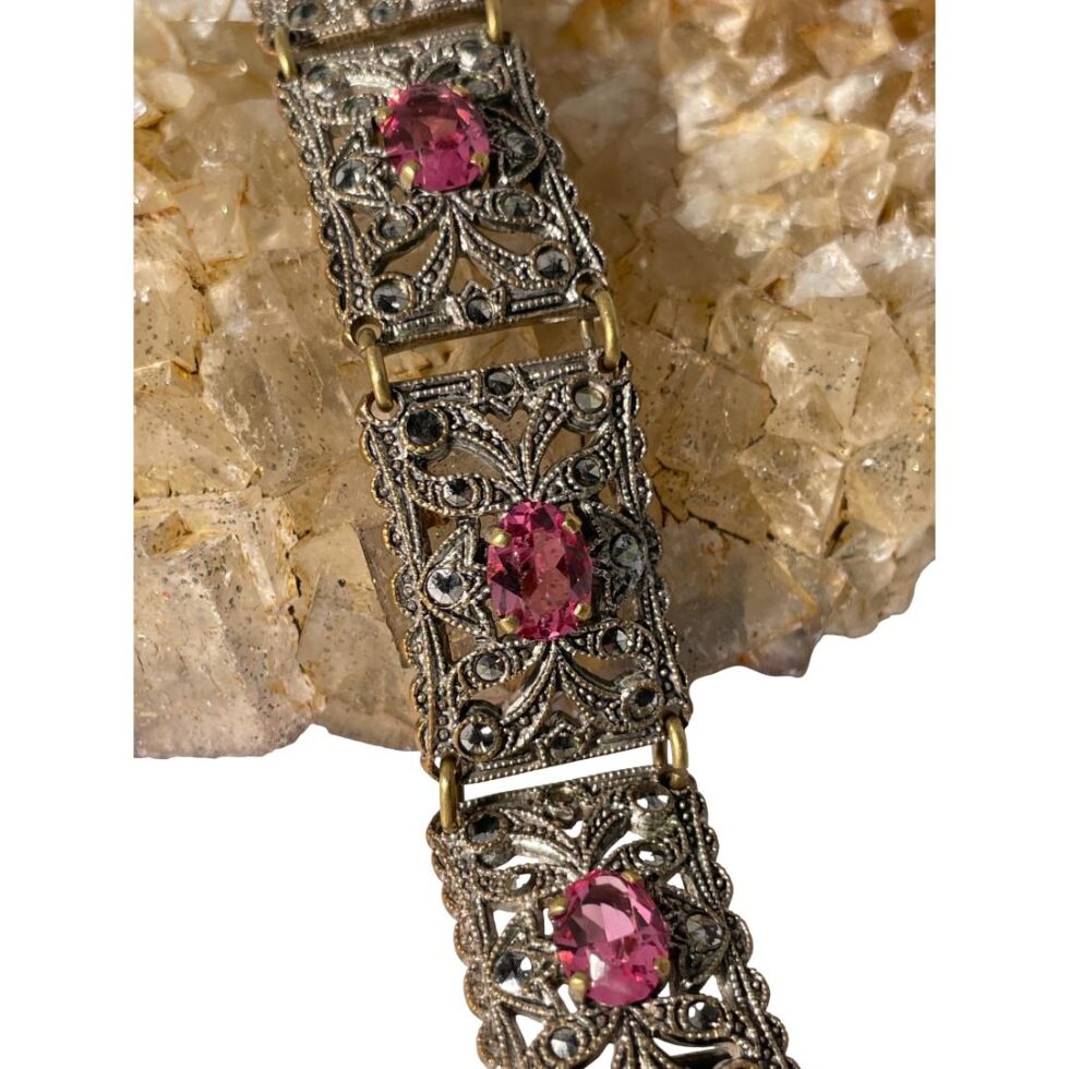 A close up of some of the panels of the Czech bracelet still shown displayed on a rock of river quartz. The pink paste stones are beautifully faceted in an oval cut.