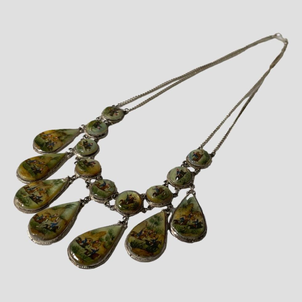 Photo of the hand-painted Persian M.O.P necklace displayed on a flat surface and laid diagonally across the page with the panels in the bottom left.