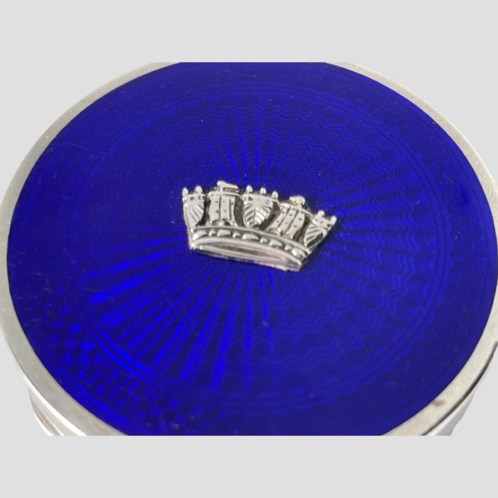 A close up photo of the blue guilloche enamel lid and naval crown.