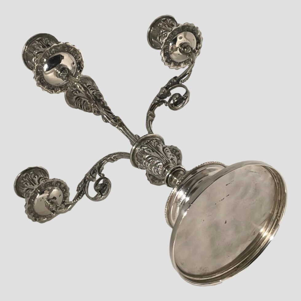 Photo of the Egyptian candelabrum laid down showing the base which is in the bottom right corner. There are no markings on the base however, you can just make out the short hallmark on the base of the wax drip plates.