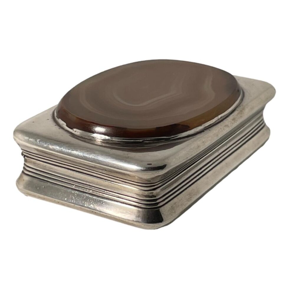 Photo of antique silver table snuffbox displayed diagonally across the page with the top closed.