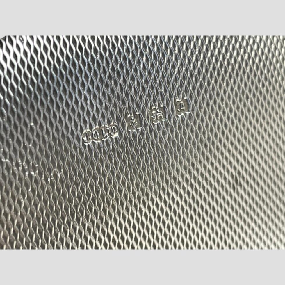 Close up photo of the full hallmark on the engine turned silver base. J.G. Ltd to the left with full Birmingham assay mark to its right.