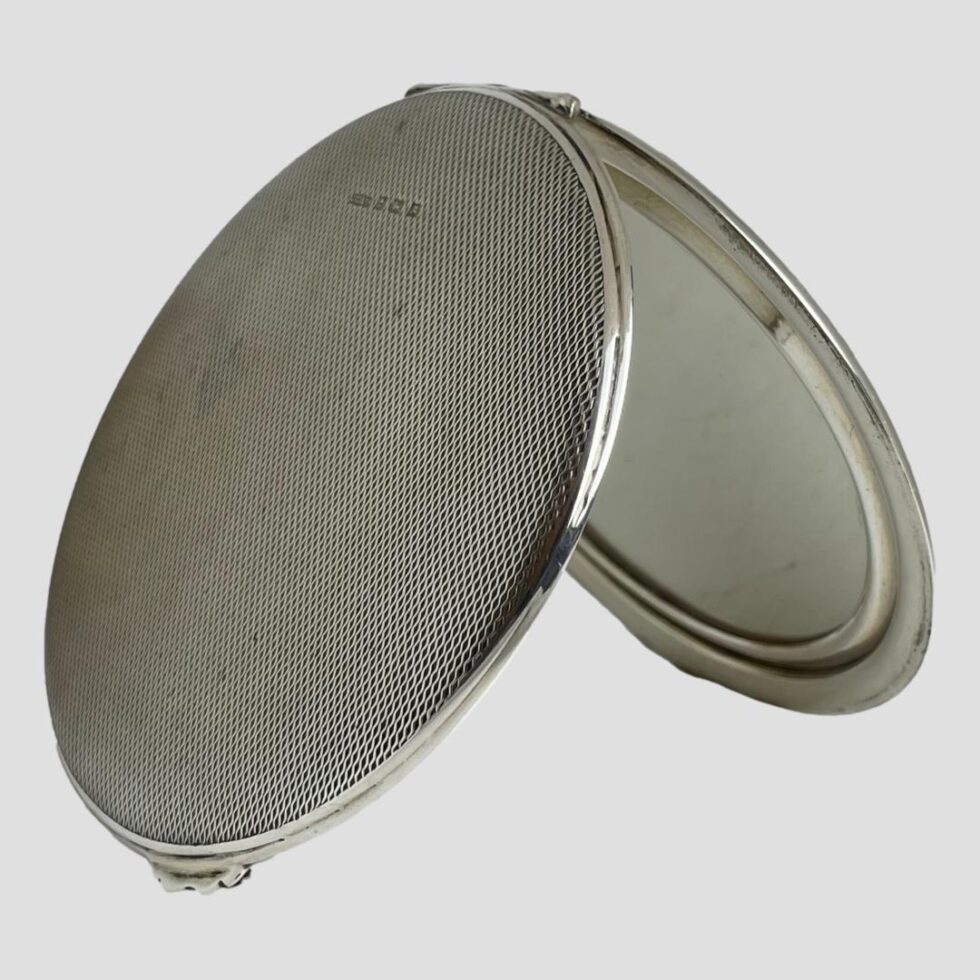 Photo of mirror compact shown open and face down propped up by itself.