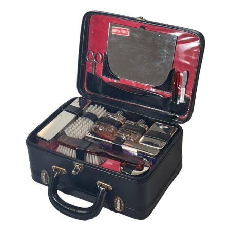 Main photo of vintage French vanity case displayed with the lid to the contents section open revealing all the pieces required for vanity on the go! This case is fully loaded with 2 scent bottles (including some contents), comb, brush, nail files, shoe horn all in their individual slots and toothbrush, razor, soap and cotton wool inside cases also, with their own slots. The mirror sits inside the lid and can be removed. The exterior of the case is black and the interior red. The tray of contents lifts out to reveal a shallow compartment probably for a small towel or flannel perhaps.