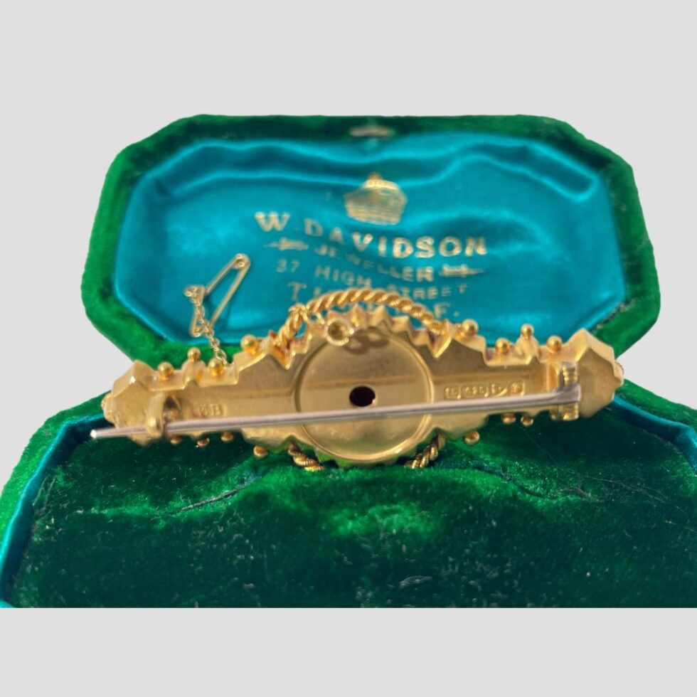 Photo of Chester gold brooch still displayed inside its box this time with the back of brooch on display. The pin is shown closed and is rose gold.