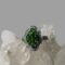Main photo of chrome diopside silver ring displayed on top of a rock of natural quartz crystal with the ring front forward facing. The ring is oval in shape with 8 outwardly curved sides. At the centre are 3 oval cut beautiful green chrome diopside stones laid vertically with the largest at the centre. To the top and bottom of these oval stones are 3 round cut stones laid 2 down 1 up like a pyramid. A frame of cubic zirconia surrounds the chrome diopside stones. A further 6 small round cut chrome diopside stones run along the shoulders of the ring in pairs so 3 rows of 2 on each shoulder. A pretty ring with an Art Deco look.