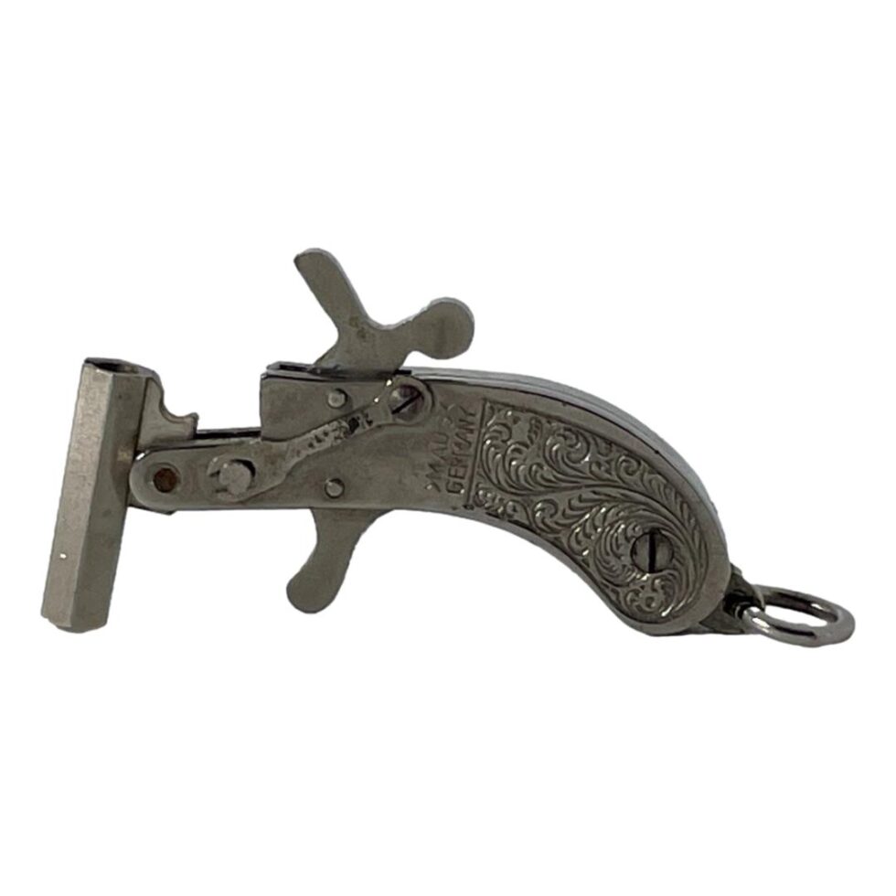 Photo of Maus flint pistol cap gun displayed upright with the barrel cocked and trigger pulled back. The handle is on the right this time.