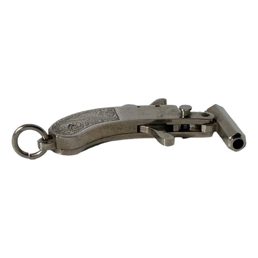 Photo of Maus cap gun pistol laid flat on its side to show the small button which opens and closes the barrel lock. The barrel is shown on the right.