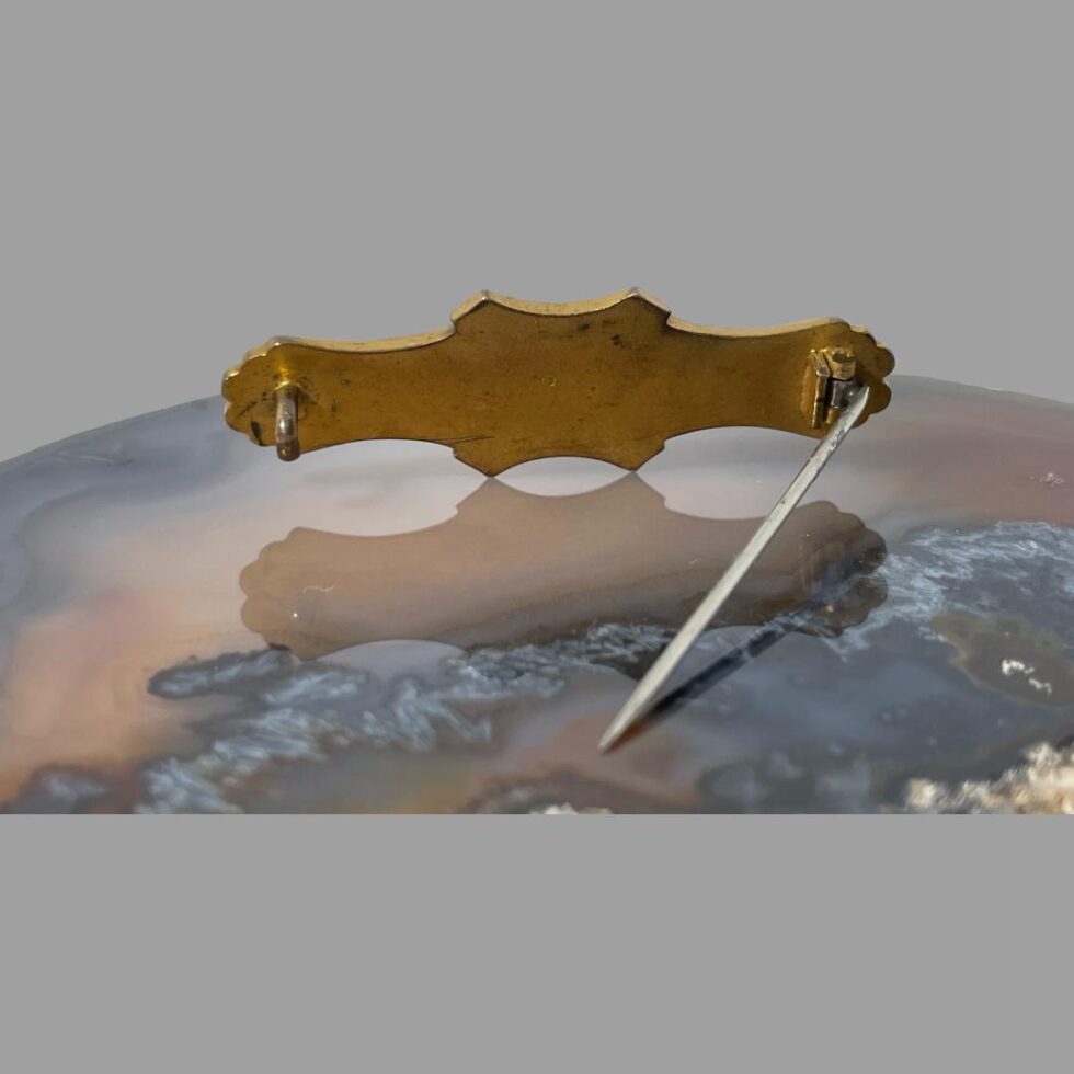 Photo of the back of the mourning brooch showing the brass backing. The brooch is still on the agate and shown upright using the pin.