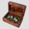 Main photo of Links silver peridot cufflinks displayed inside their wooden box with all the main sides of the cufflinks on display (all sides with peridot) The box appears to be a walnut burr and is a rich orangey brown and there is some green felt like material inside the box with black elastic where the cufflinks are threaded though.