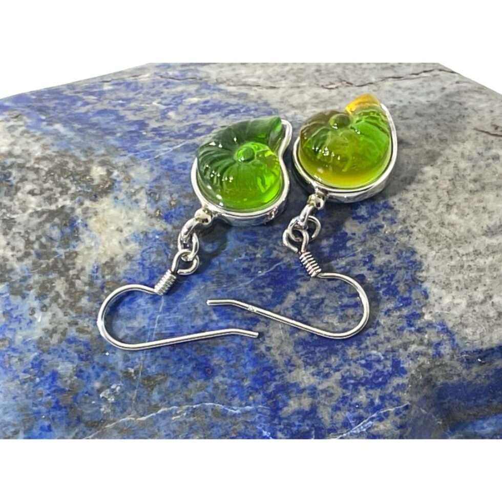 Photo of the shell earrings displayed on top of a rock of natural lapis lazuli. The green pate-de-verre- crystal shells contrasts well with the blue of the lapis ocean.