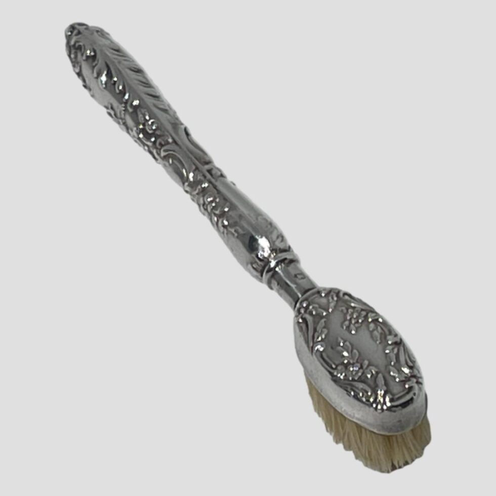 Photo looking down along the top of the moustache brush. The brush end is in the bottom right corner with the handle tip in top left. The embossed design to the whole brush.