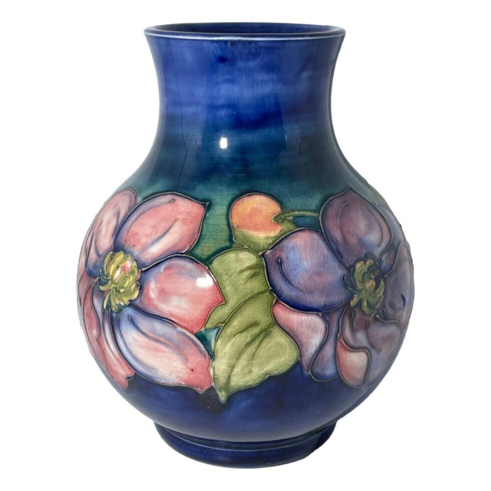 Another eye level photo of the Moorcroft vase this time with different set of clematis flowers on display. Pink to the left, purple to the right with a orangey pink bud at centre top.