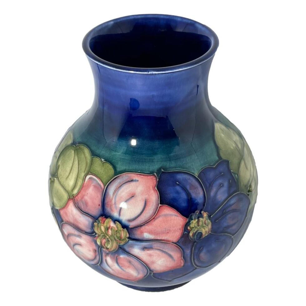 A photo now at a more raised angle looking diagonally downward. The last flower combination is on display and the mouth of the vase is more visible. Here we have 2 flowers together at centre, pink on left and blue on right with light green foliage on either side of these.
