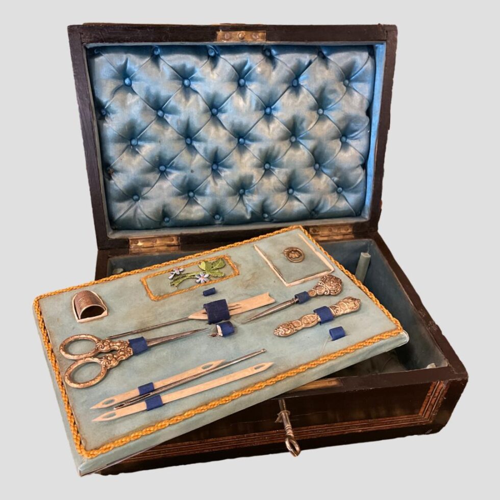 Photo of open sewing box with tray lifted and laid diagonally across the lower section of box.