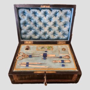Main photo of Palais Royale sewing box seen with lid open revealing the tray of contents and the padded pale blue silk lining in the lid. The tray is mostly complete with its sewing instruments with just 2 or 3 gaps which are visible. Not bad considering it's coming up for 200 years old fairly soon!