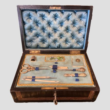 Main photo of Palais Royale sewing box seen with lid open revealing the tray of contents and the padded pale blue silk lining in the lid. The tray is mostly complete with its sewing instruments with just 2 or 3 gaps which are visible. Not bad considering it's coming up for 200 years old fairly soon!