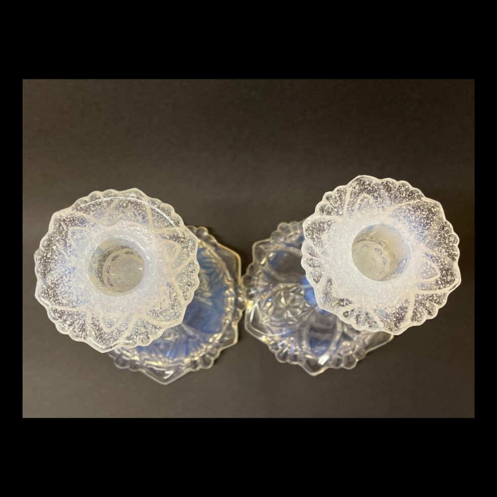 Photo looking straight down at both candlesticks which are still side by side from above. The sconce areas have flecks of white and some blue tinge which gives an impression of snow.