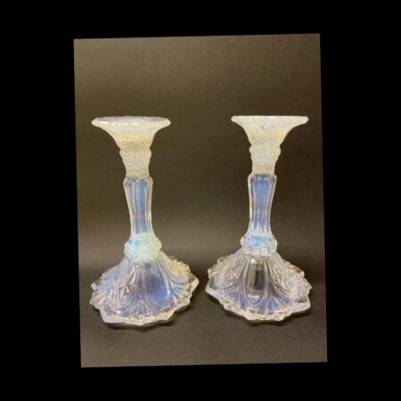 Main photo of 1930s Vaseline glass candlesticks displayed side by side at an eye level. The sconce area appears white but has flecks of white and blue and below the sconce the candlesticks are an almost luminescent Vaseline blue. The background is a dark grey to show up the colours of the candlesticks better.